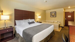A hotel room with a large bed, bedside lamps, a bathroom with a bathtub, and a desk with a chair.