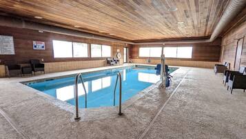Ein Hallenbad mit Holzboden und -wänden, klaren Fenstern und einem Rettungsschwimmerstuhl.