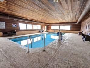 An indoor swimming pool with wooden ceiling and walls, clear windows, and a lifeguard chair. - Cobblestone Inn & Suites Merrill (Merrill)