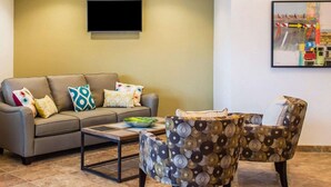 A living room with a sofa, two patterned armchairs, a coffee table, and a flat-screen TV mounted on the wall. - Quality Inn Streetsboro - Kent (Streetsboro)