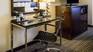 A hotel room with a desk, chair, television, and a minibar. - Quality Inn Streetsboro - Kent (Streetsboro)