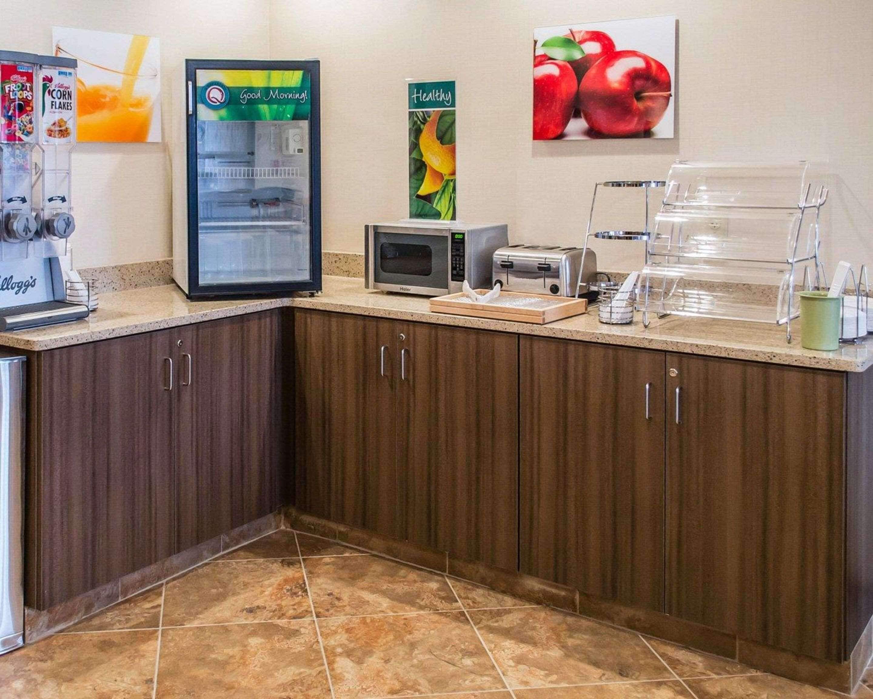 Een keukenhoek met een koelkast, magnetron, broodrooster en een presentatie van fruit.