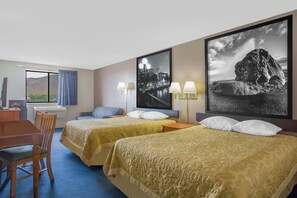 Une chambre d’hôtel avec deux lits, un bureau et des chaises. Il y a deux lampes sur le bureau et une fenêtre avec des rideaux.