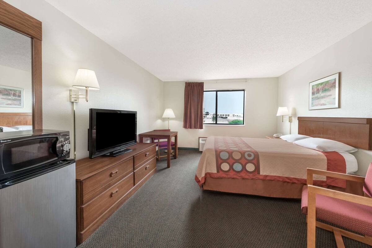 Ein Hotelzimmer mit Bett, Fernseher, Mikrowelle, Schreibtisch und einem Fenster mit Aussicht.