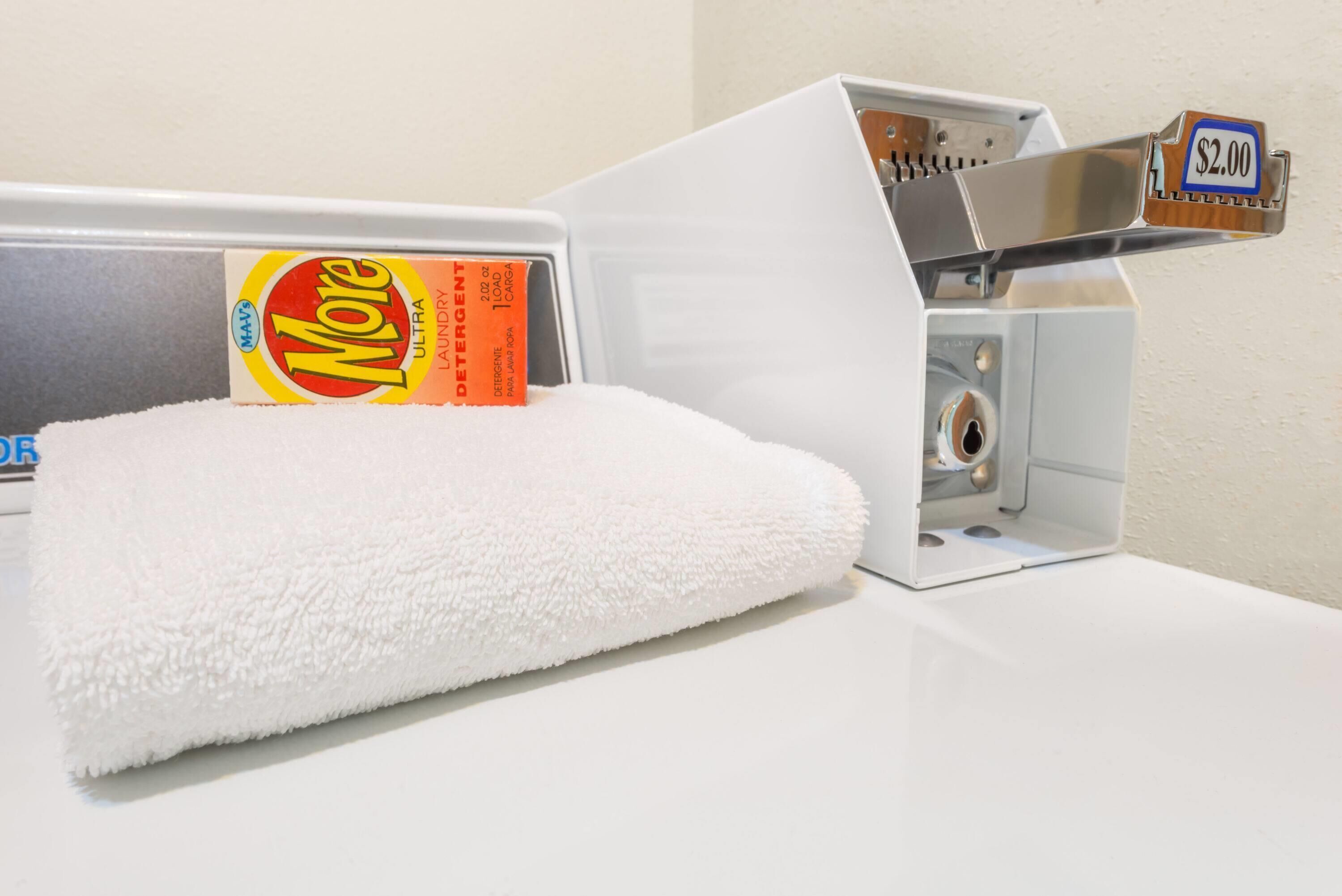 A white towel on a counter, a box of More laundry detergent, and a metal object with a price tag.