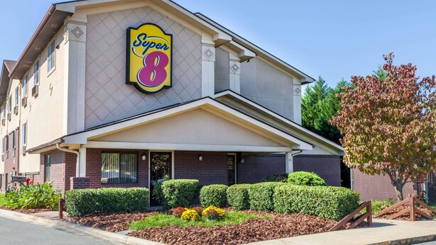 Un hotel Super 8 con un letrero llamativo, fachada de ladrillo y un jardín delantero cuidado.