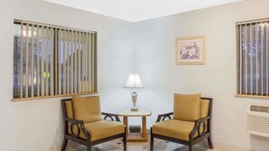 Una habitación con dos sillones, una mesa redonda pequeña, una lámpara y un cuadro en la pared.