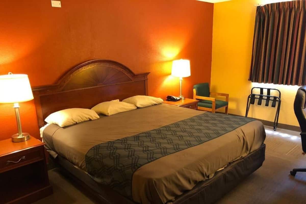 Ein Hotelzimmer mit Bett, Nachttischlampen, einem Sessel und einem Schreibtisch.