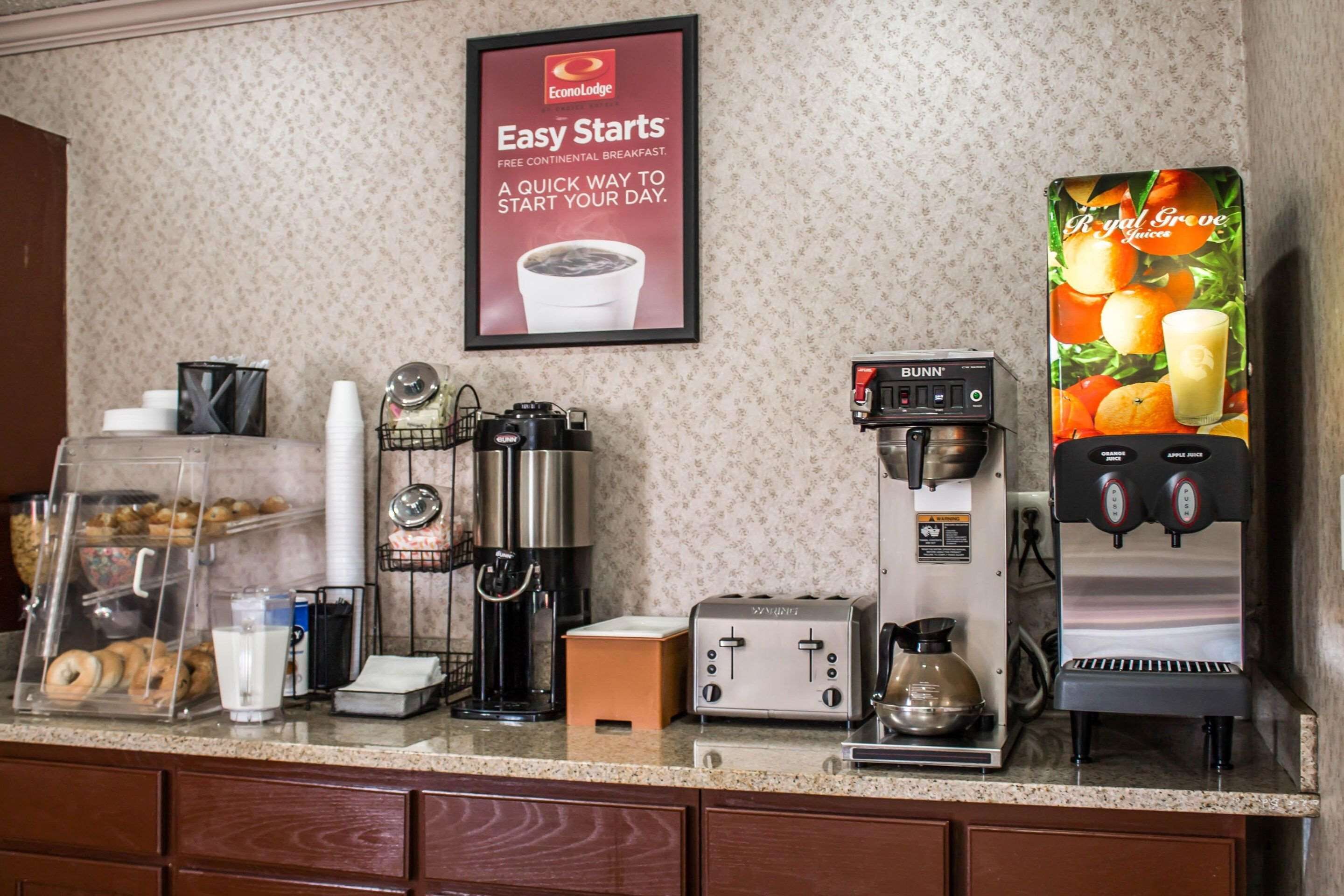 A breakfast bar with a coffee machine, a toaster, and a display case with pastries.