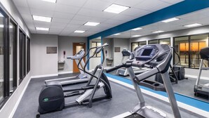 A gym with treadmills, ellipticals, and a mirrored wall.