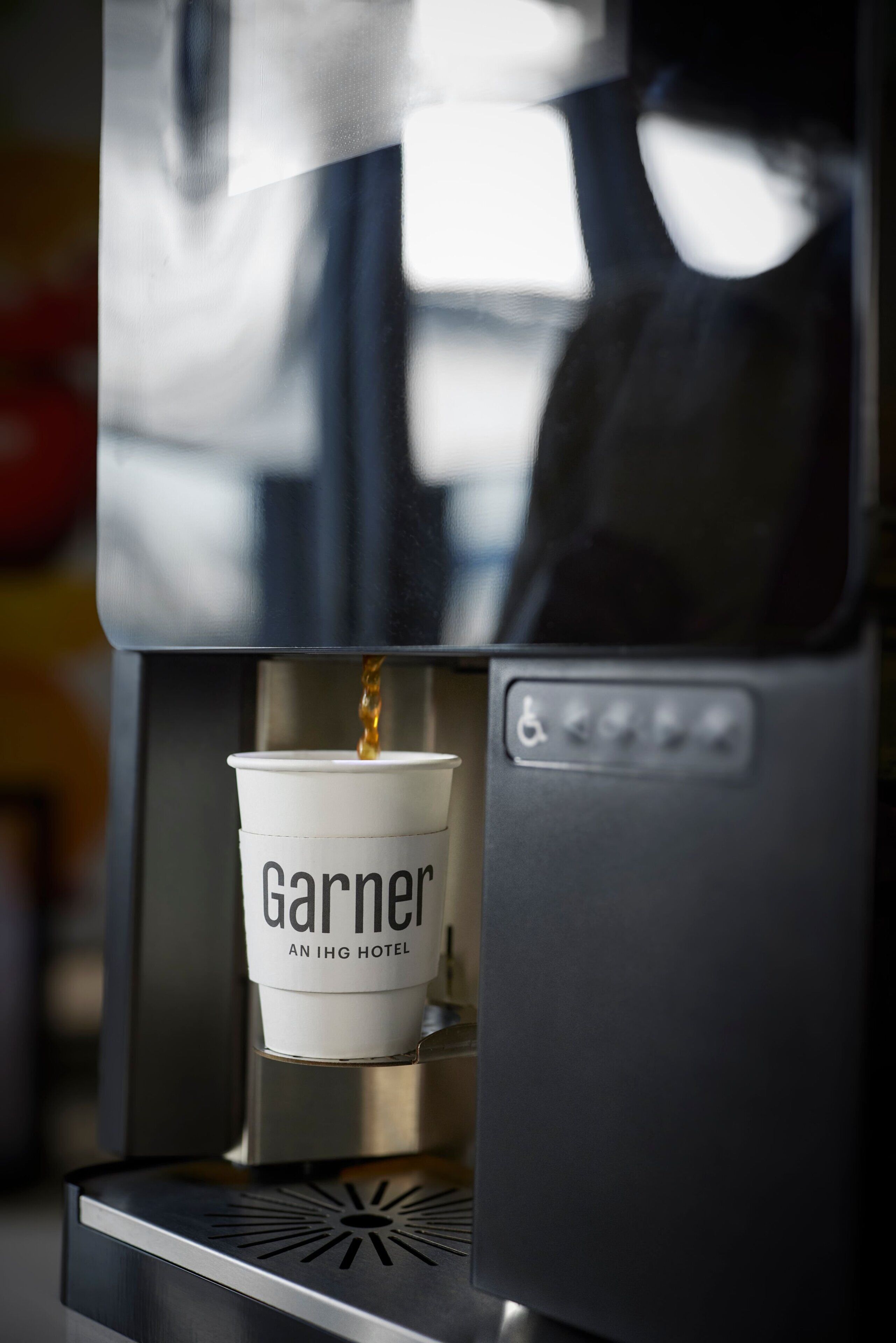 A coffee machine dispensing coffee into a cup labeled 'Garner AN IHG HOTEL.'