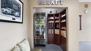 A market area with a refrigerator, shelves stocked with snacks, and a framed picture on the wall. - Super 8 by Wyndham St. Clairsville OH/Wheeling WV Area (St. Clairsville)