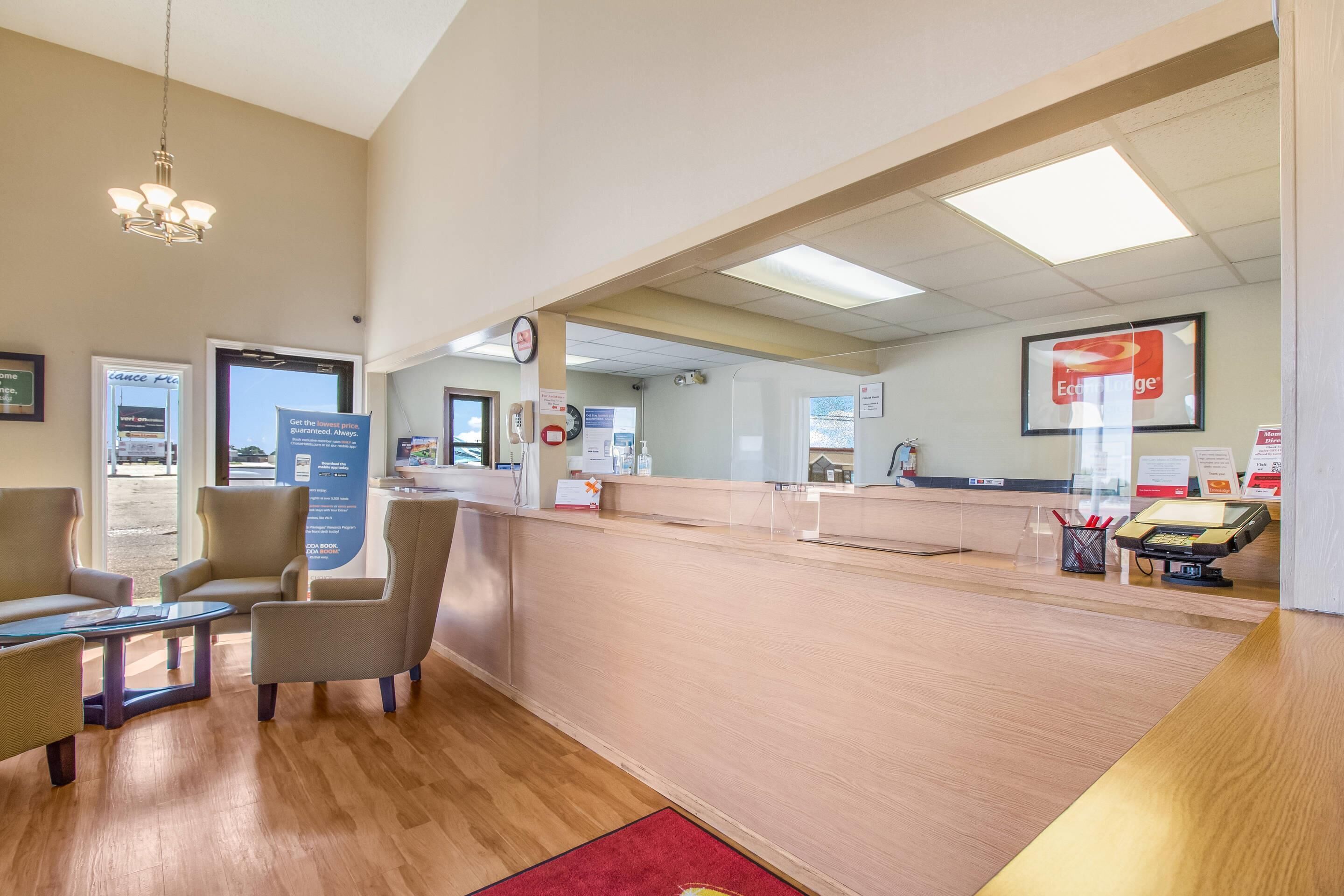 A reception area with a wooden reception desk, a clock, and a sign for 'EAT & LEAVE'.