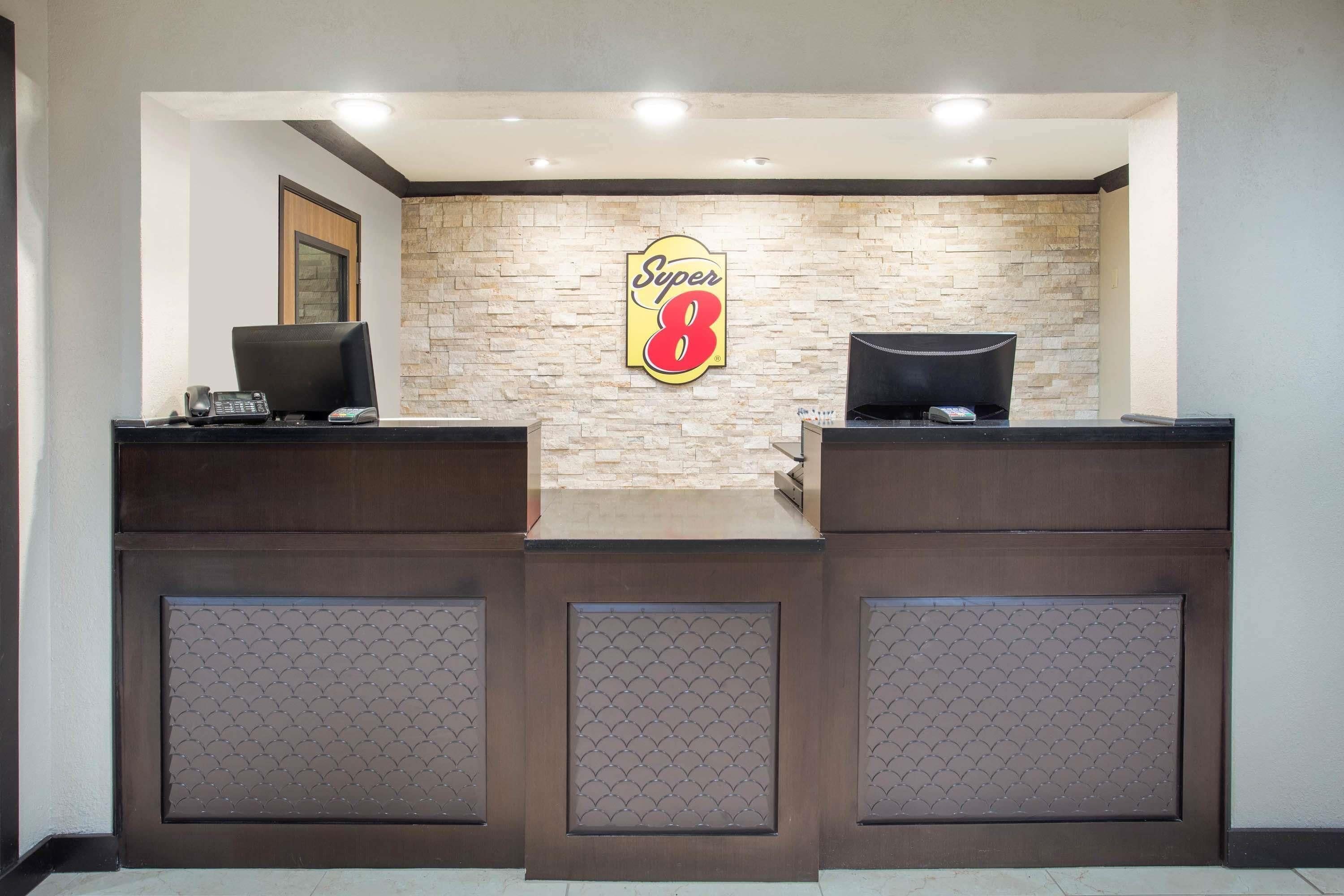 Una recepción con el logotipo de Super 8, dos monitores de computadora y un teléfono.