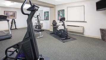 Una palestra con tapis roulant, cyclette e pesi liberi.