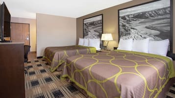 Ein Hotelzimmer mit zwei Betten, einem Schreibtisch, einem Fernseher und zwei großen Landschaftsbildern an der Wand.