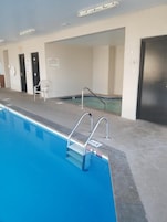 A swimming pool with a metal ladder, a white chair, and a door in a building.