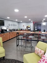 A modern kitchen with a bar area, wooden cabinets, and a flat-screen TV.