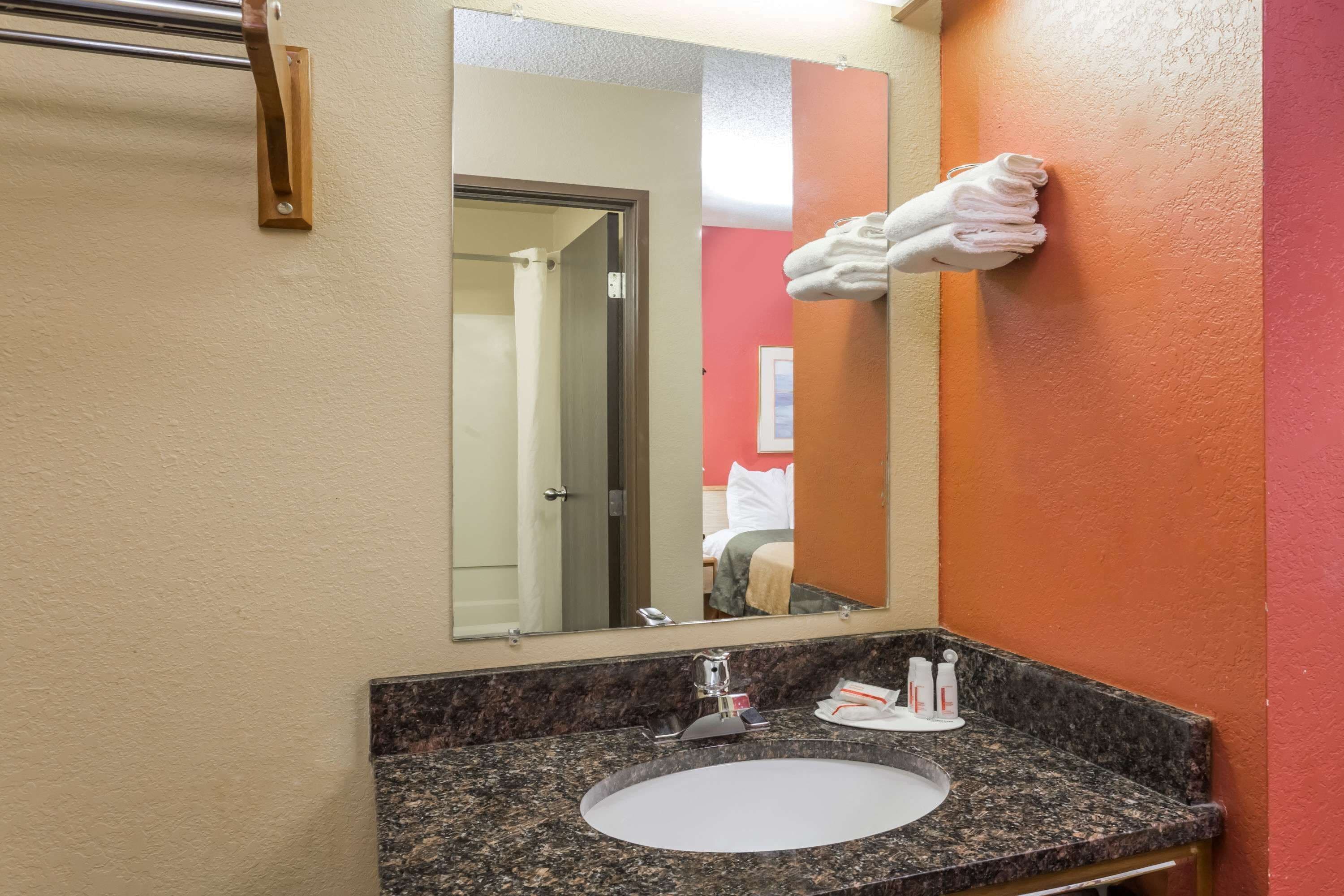 A bathroom with a sink, mirror, and towel rack.