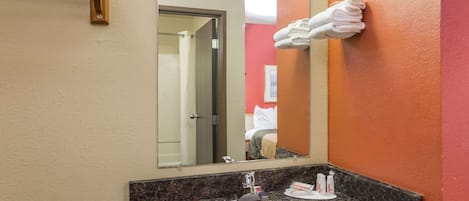A bathroom with a sink, mirror, and towel rack.