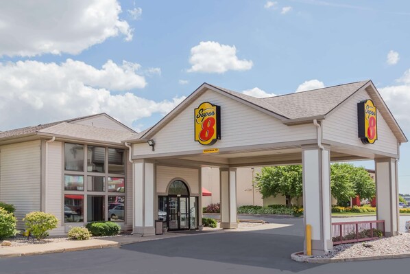 A Super 8 motel with a covered parking area, a drive-through window, and a clear sky.