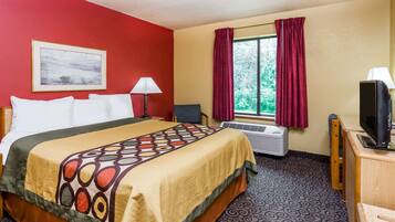Una habitación de hotel con cama, escritorio con televisor, silla, ventana con cortinas, aire acondicionado y un cuadro en la pared.
