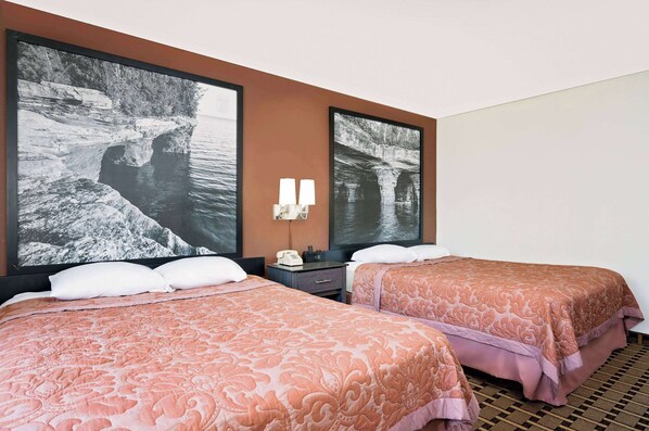 A hotel room with two beds, a nightstand, a telephone, and two wall-mounted lamps.