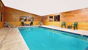 Ein Poolbereich mit Holzwänden, einem Pool und mehreren Stühlen.