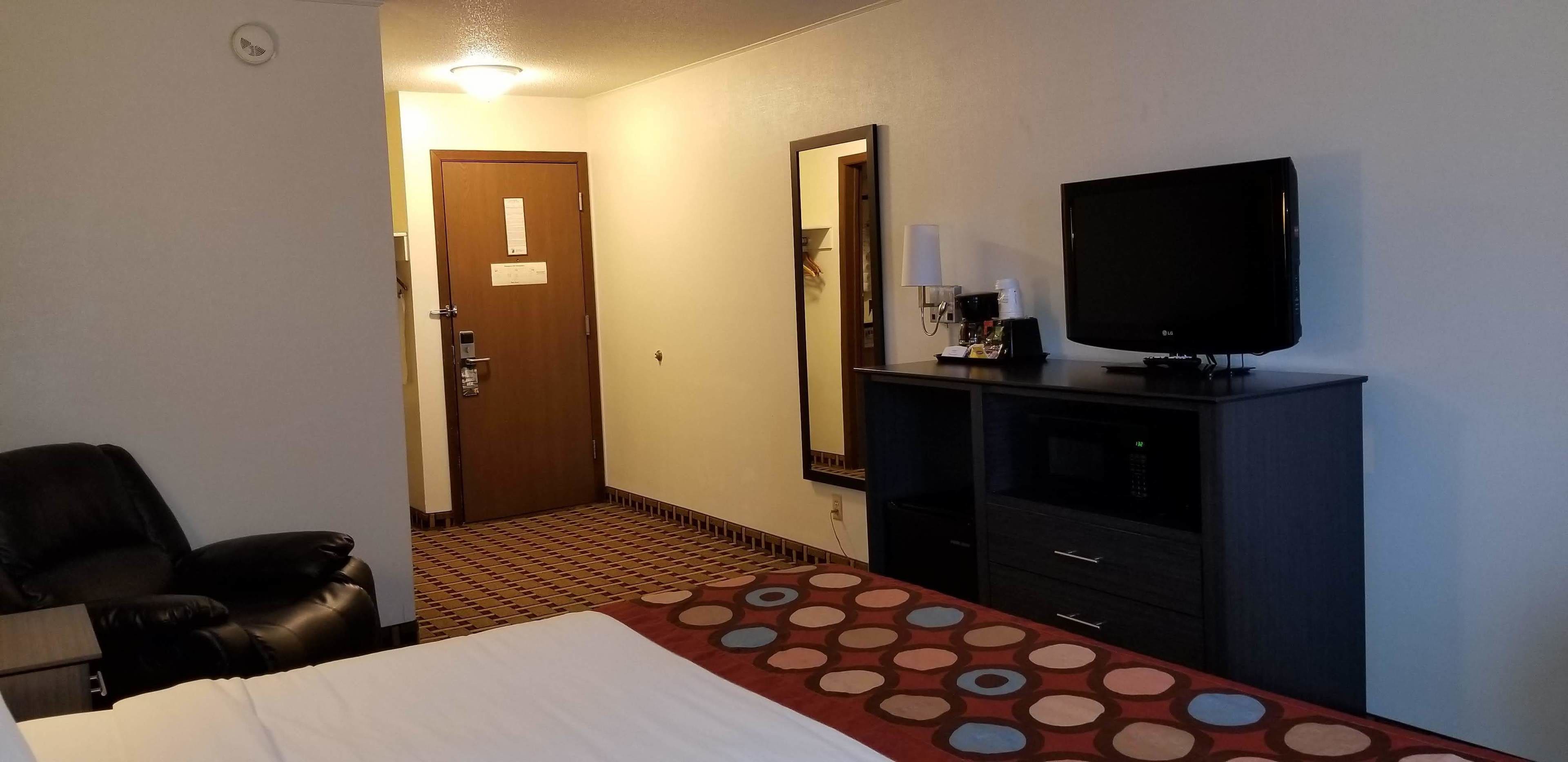 Hotellihuone, jossa on sänky, televisio, työpöytä, tuoli ja ovi.