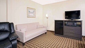 Ein Hotelzimmer mit Ledersofa, einer kleinen Anrichte mit Fernseher und einem gemusterten Boden.