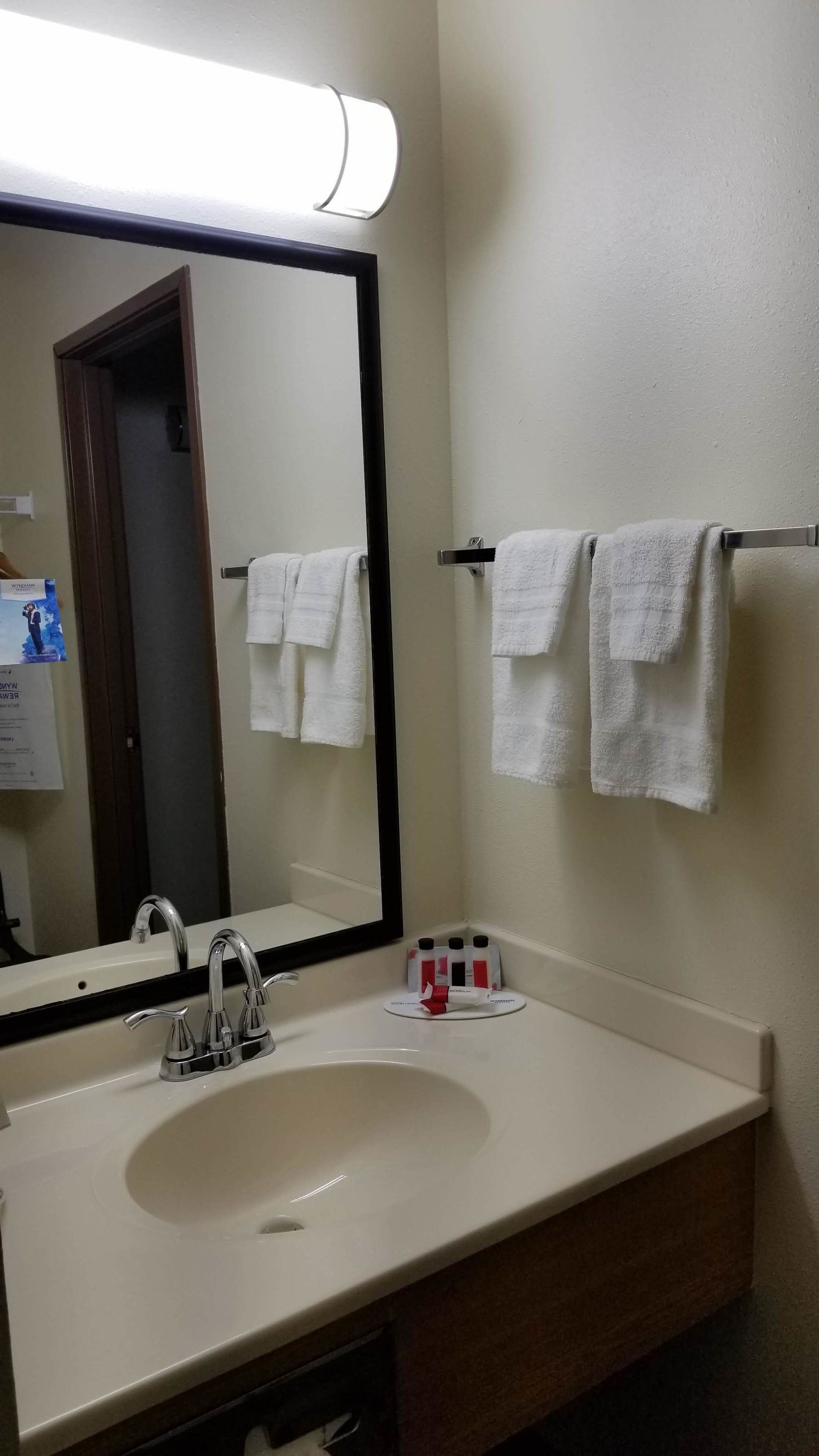 A bathroom with a sink, mirror, and towel rack.