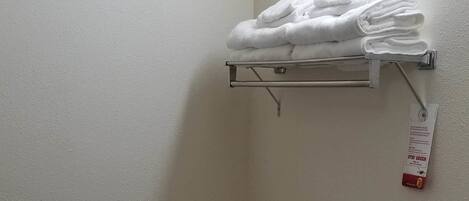 Un baño con inodoro, un perchero con toallas dobladas, un dispensador de papel higiénico y un rollo de papel higiénico.