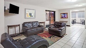 A living room with two leather sofas, a flat-screen TV, a framed mirror, and a dining area with chairs and a table. - Super 8 by Wyndham Nashville/ Dntn/ Opryland Area (Nashville)