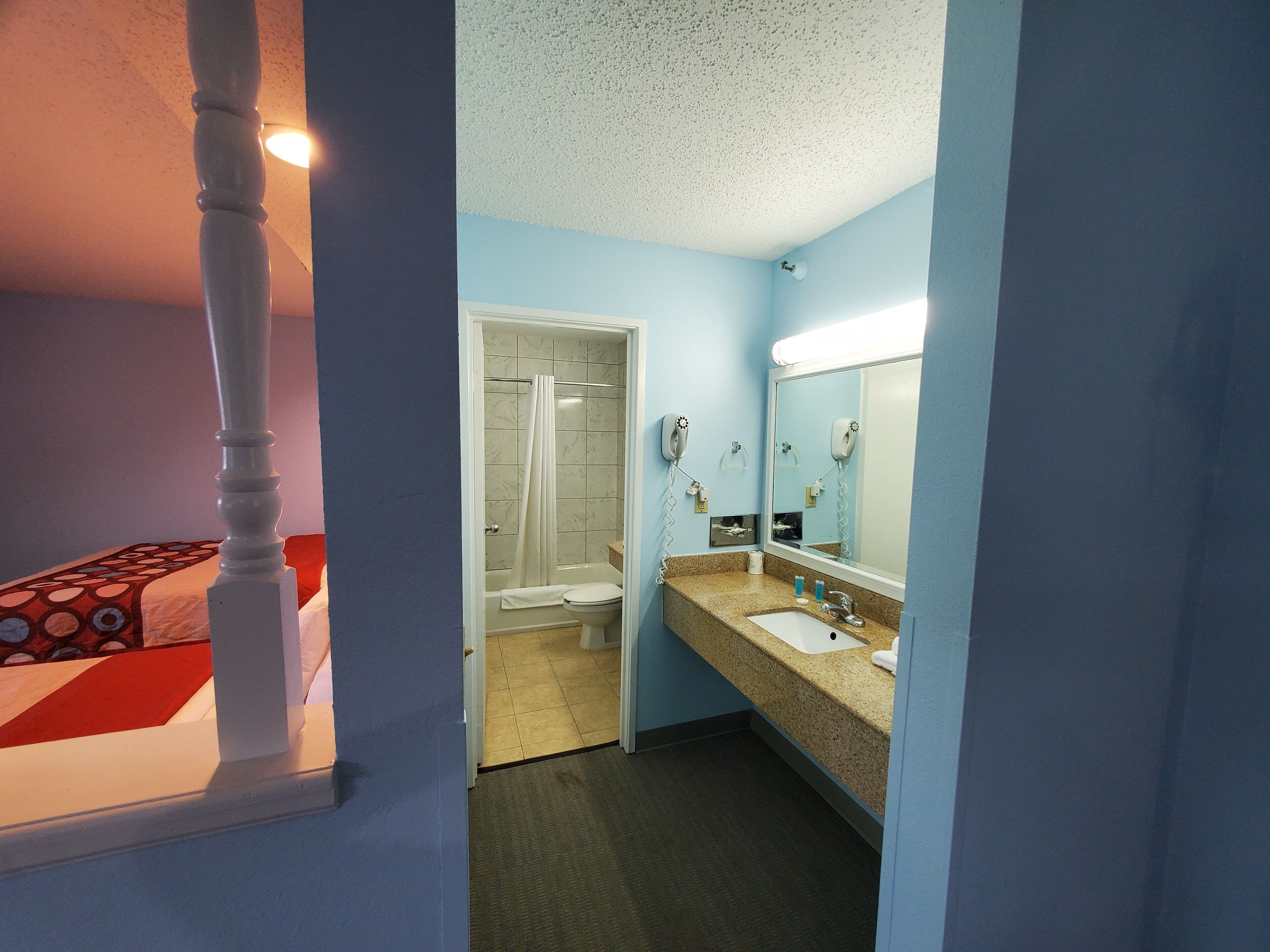 A hotel bathroom with a sink, mirror, and shower.