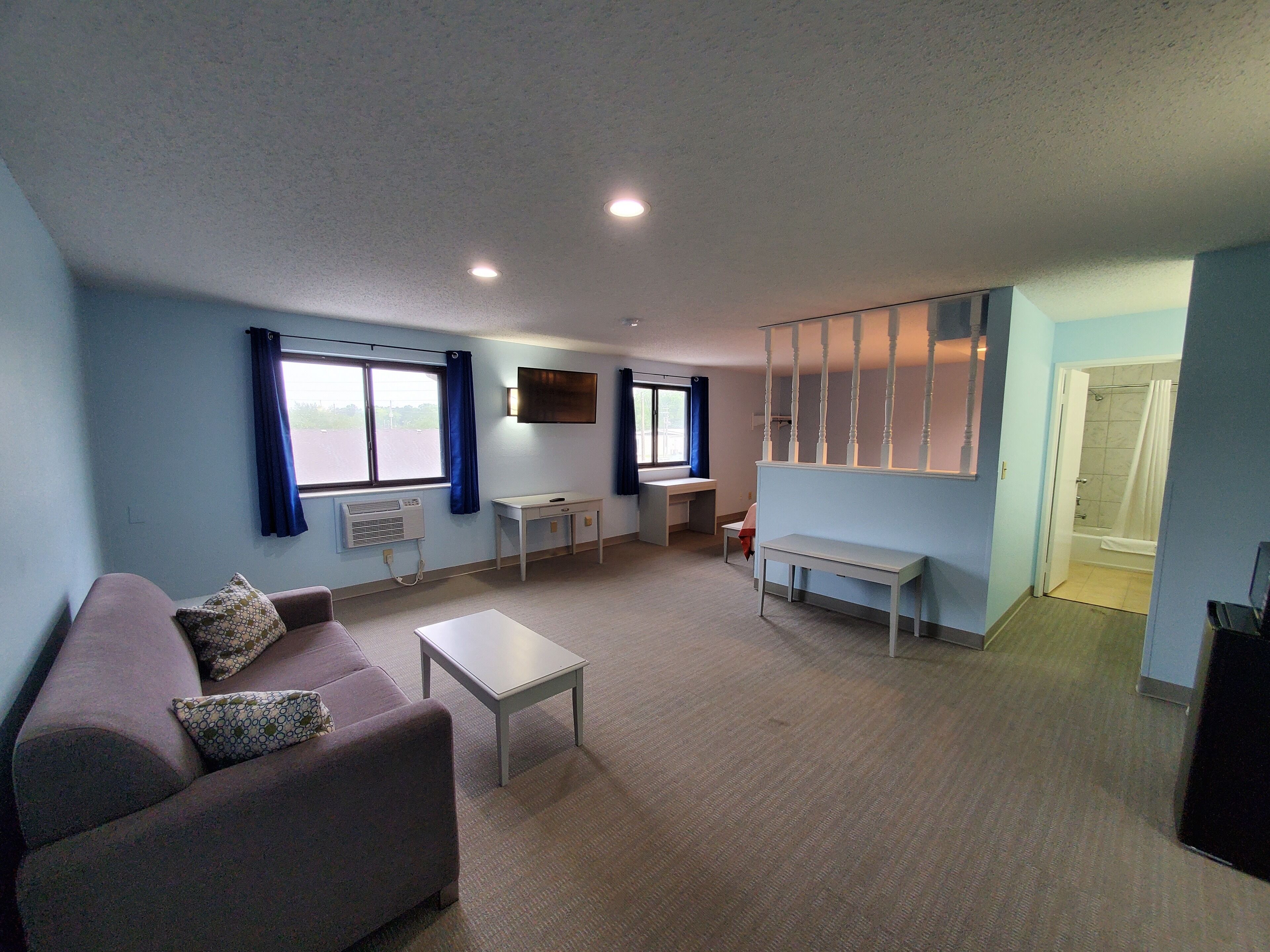 A living room with a sofa, a coffee table, a TV, and a window with curtains.
