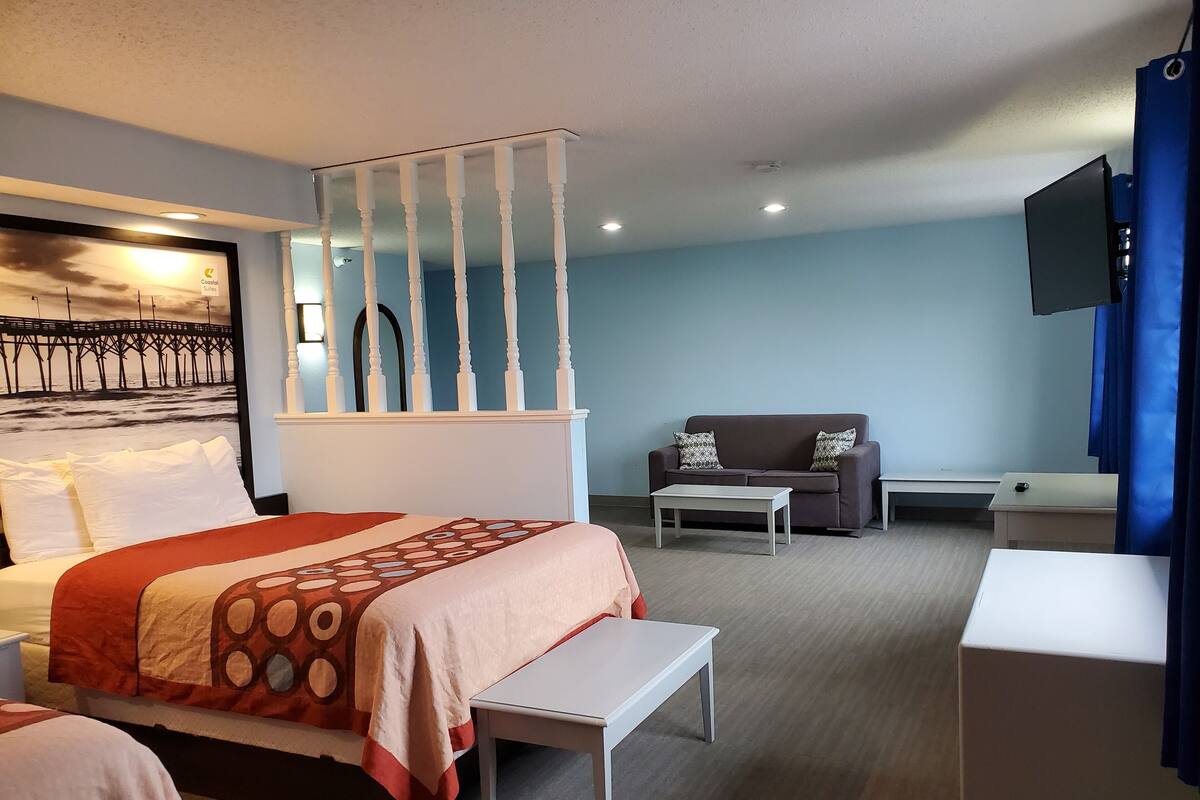 Ein Hotelzimmer mit Bett, Sofa, Schreibtisch und Fernseher.