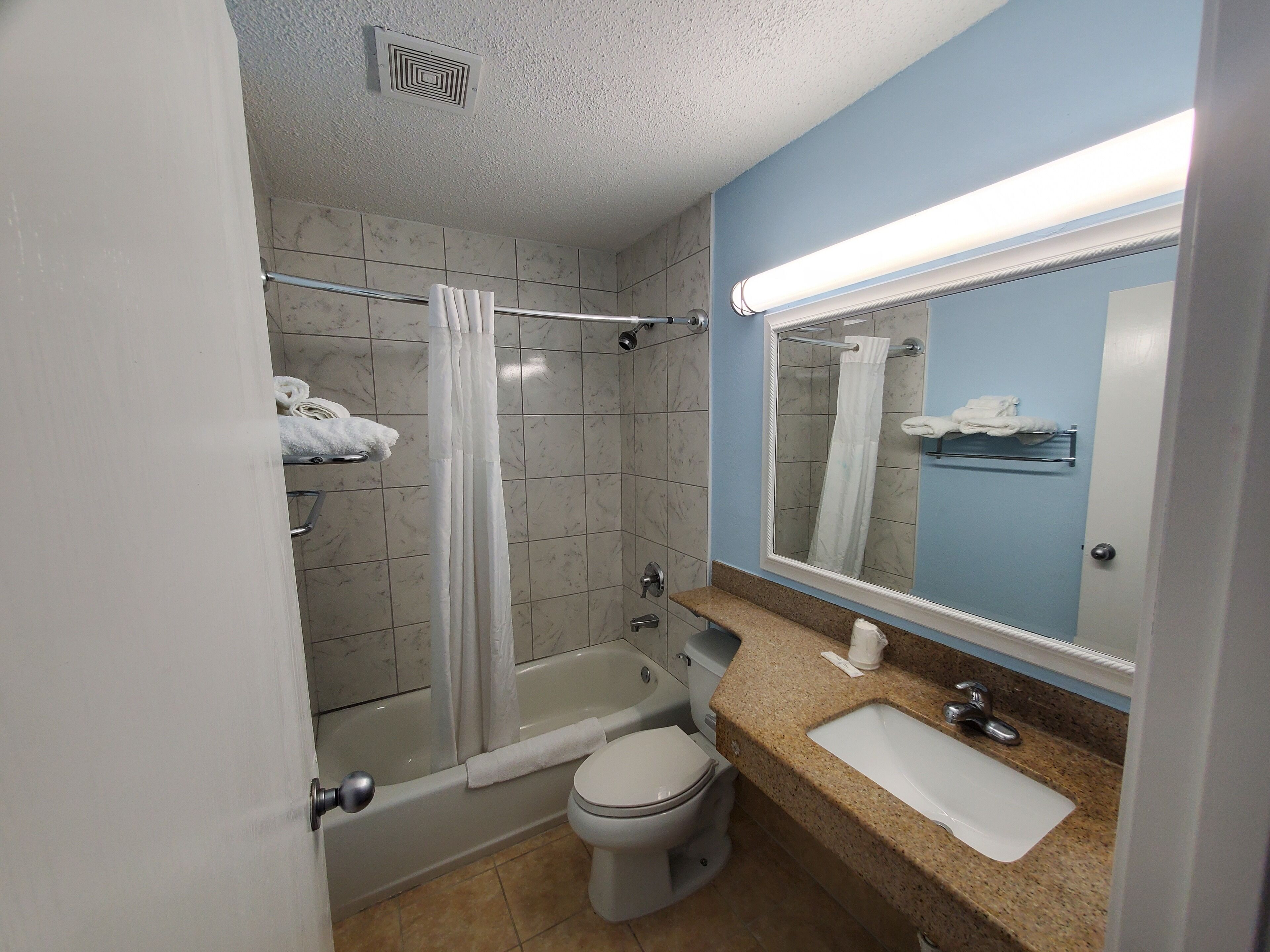 A bathroom with a bathtub, toilet, sink, and a mirror.
