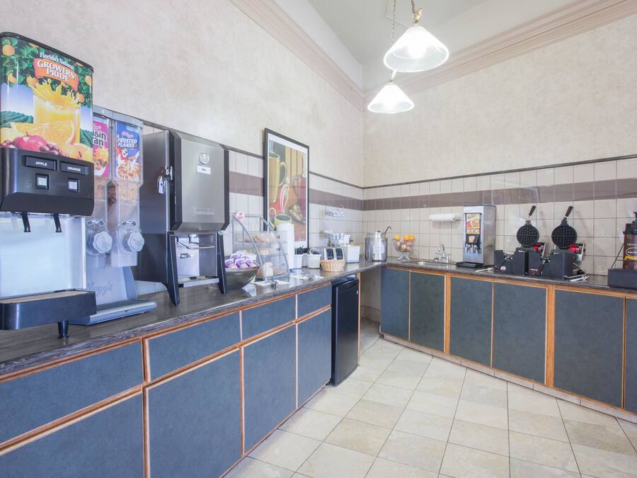 A commercial kitchen with a coffee machine, a juice dispenser, and a waffle maker.