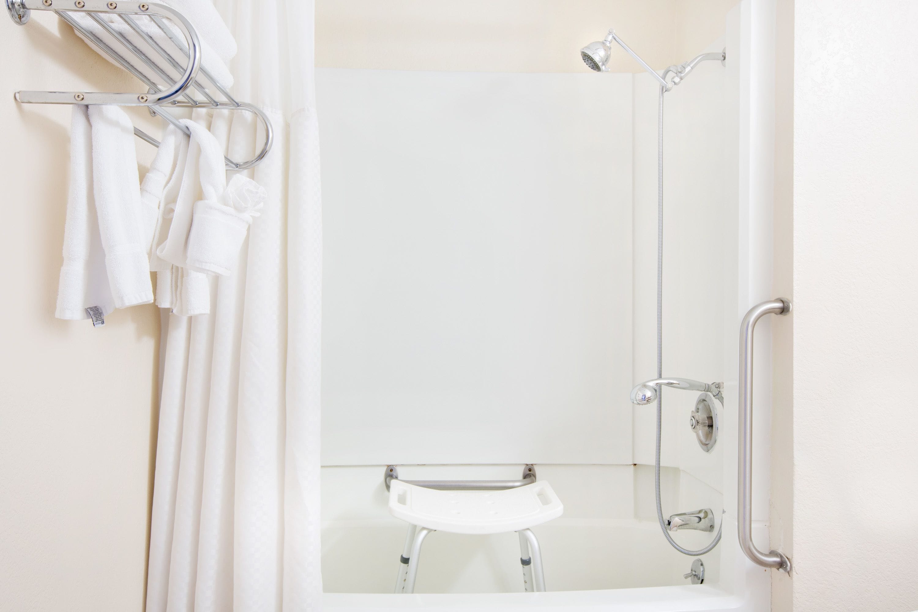 A bathroom with a shower, a sink, and a towel rack with towels.