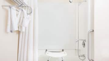 A bathroom with a shower, a sink, and a towel rack with towels.