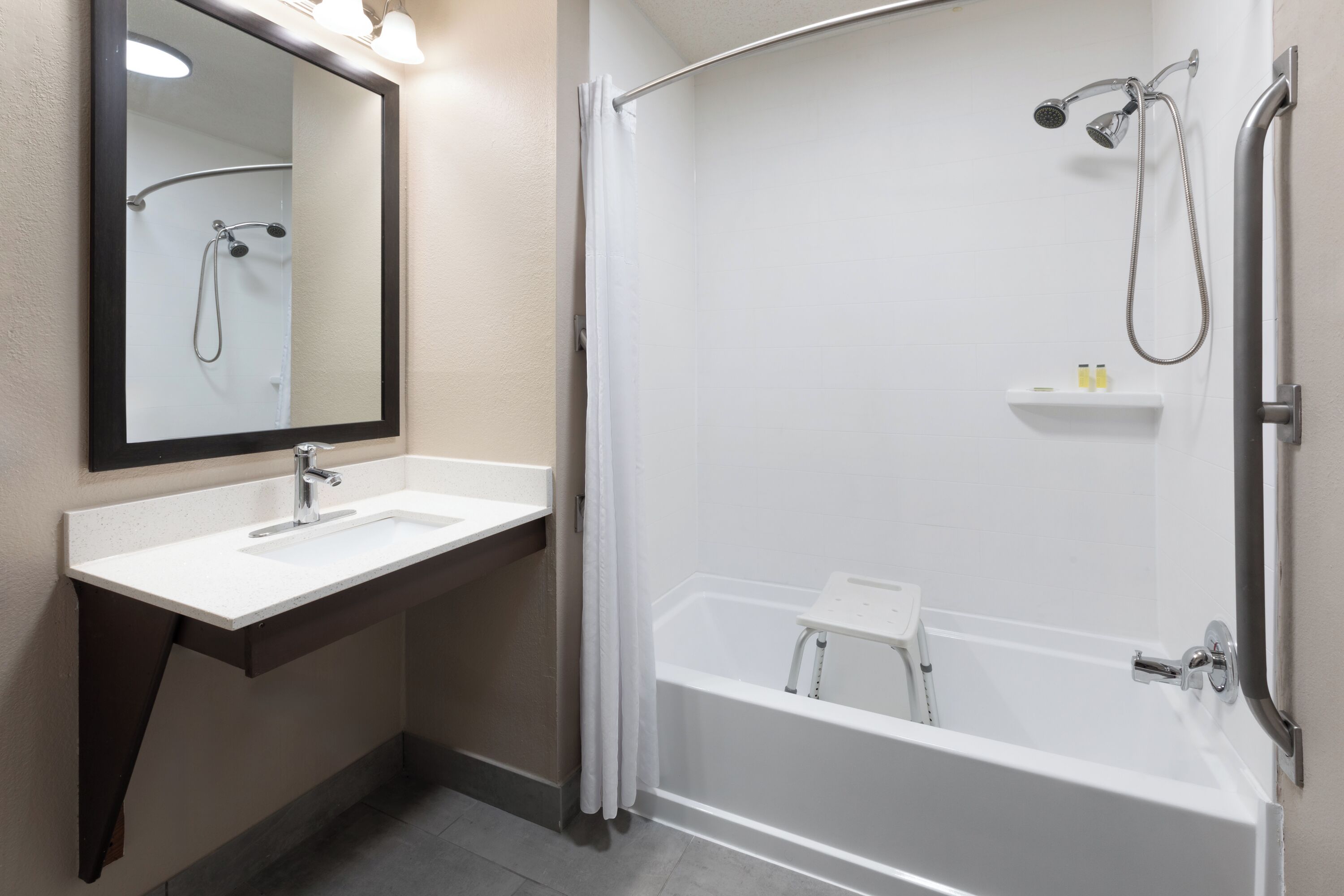 A modern bathroom with a white sink, mirror, and bathtub.