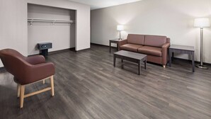 Een moderne woonkamer met een bruine leren bank, een houten stoel, een salontafel en twee bijzettafels met lampen.