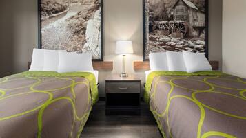 Habitación de hotel con dos camas, una mesita de noche con lámpara y dos cuadros grandes en la pared.