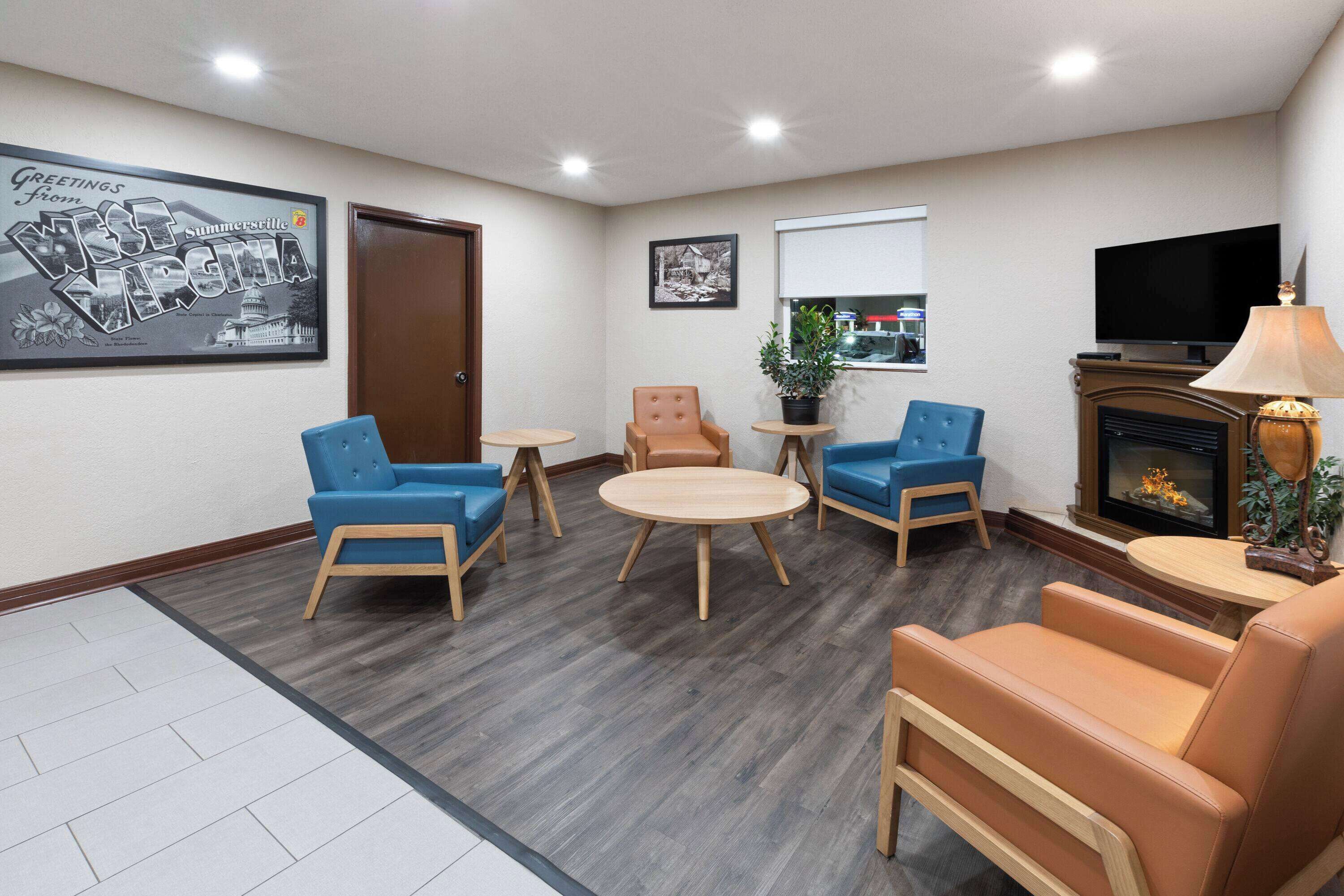 Habitación de hotel con chimenea, televisión y zona de estar con sillas azules y marrones.