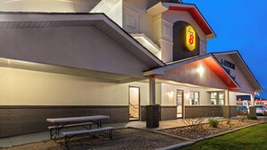 Een Super 8 hotel met een plat dak, een overdekte buitenruimte en een goed verlichte ingang.