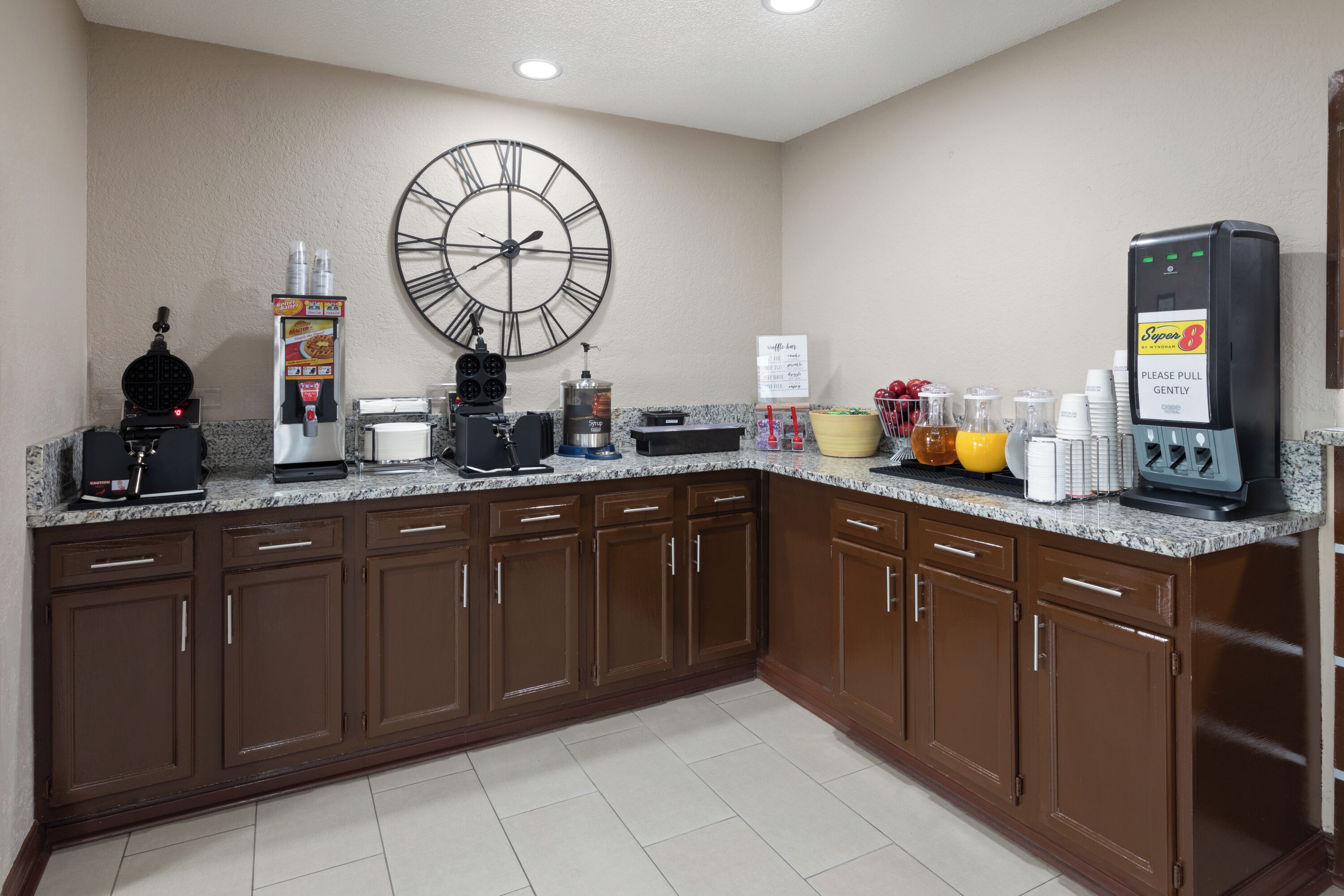 Una cocina de hotel con reloj, máquina de café y zona de autoservicio.