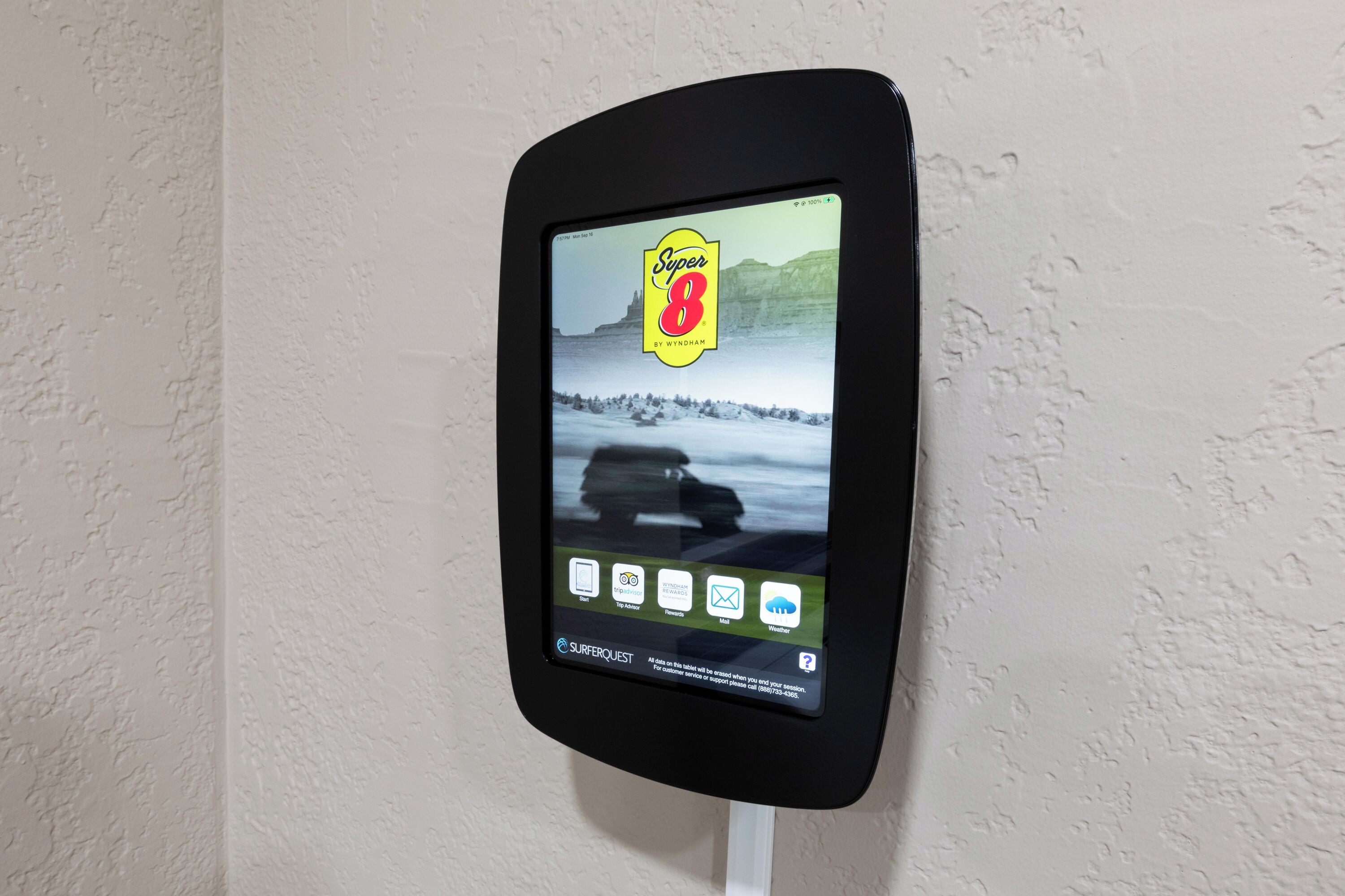 A digital kiosk with a Super 8 by Wyndham advertisement, displaying various travel options and a contact number.