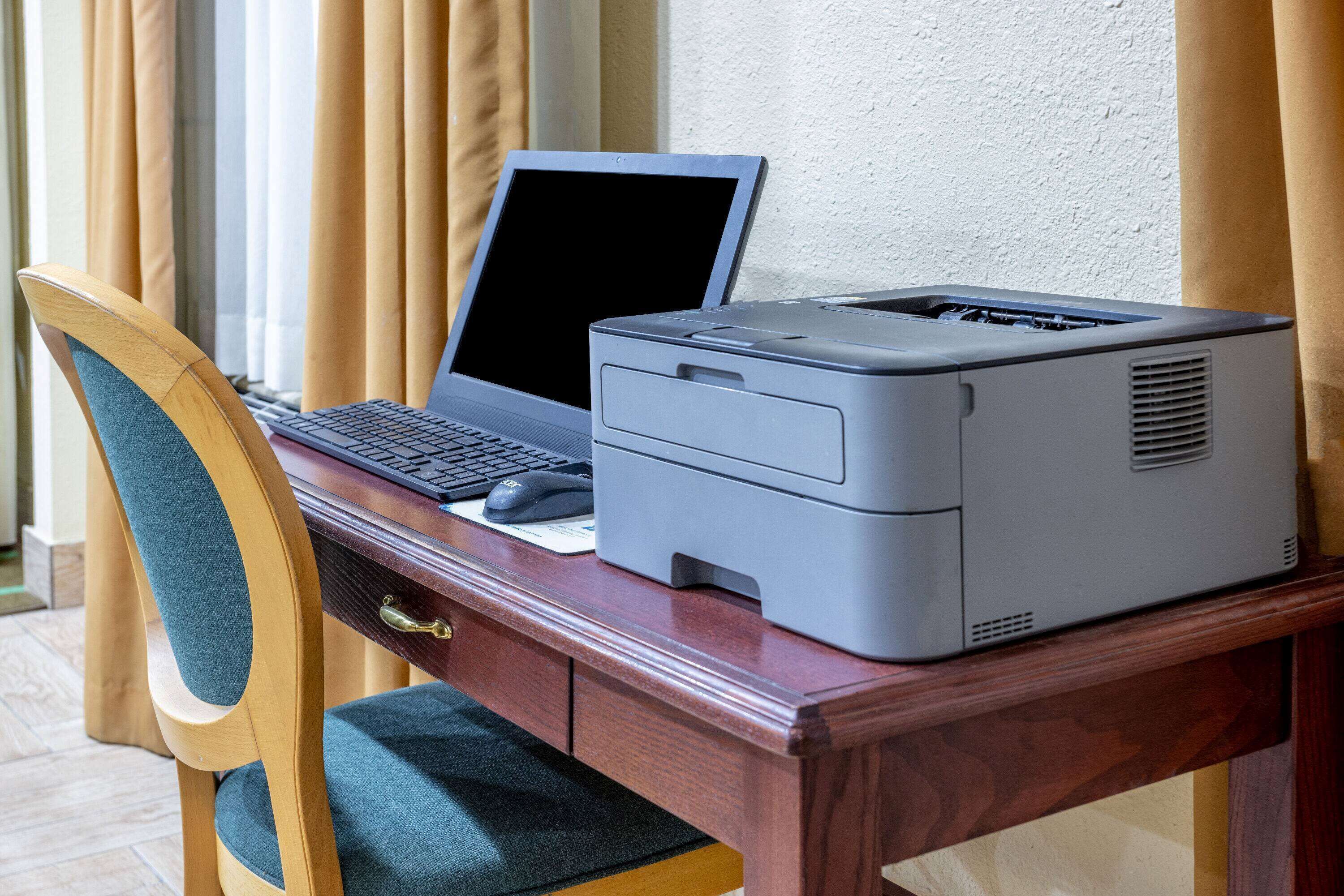 Un bureau en bois avec un ordinateur portable et une imprimante.