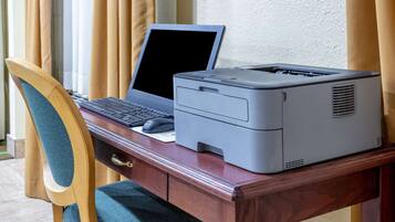 Un escritorio de madera con una computadora portátil e impresora.