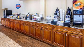 A breakfast bar with coffee machines, a TV, and a sign for the breakfast corner.
